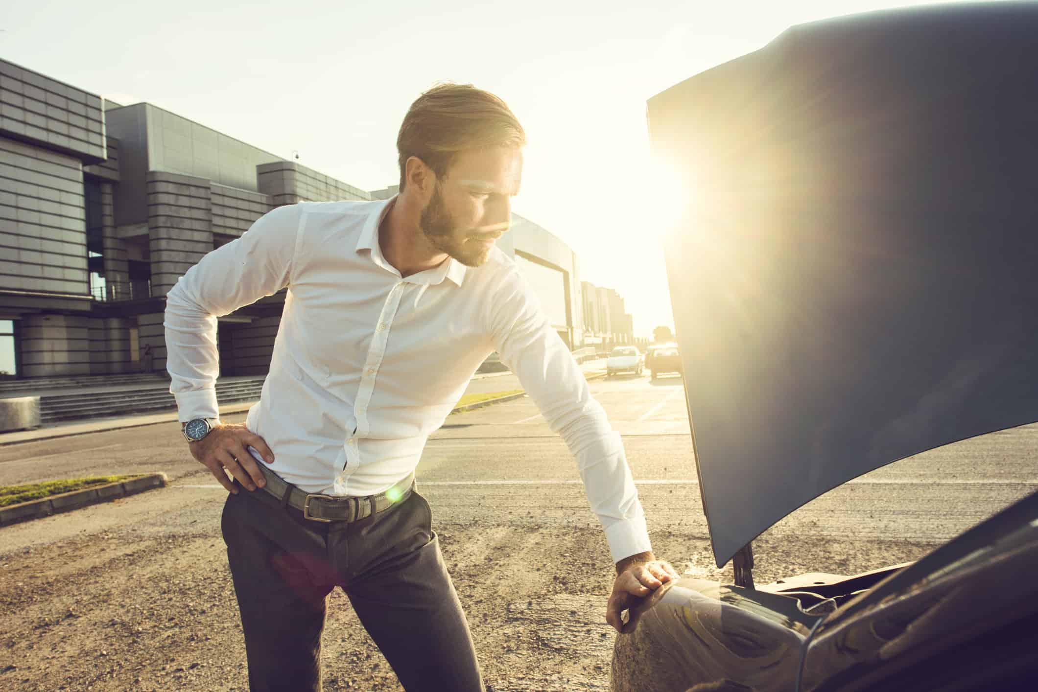 Worried businessman standing next to his broken car and thinking what to do.